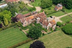 an aerial view of a large house surrounded by lush green fields and trees in the distance