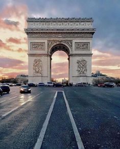 the arc triumph in paris at sunset with cars driving around it and people walking on the sidewalk