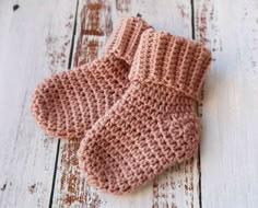 a pair of pink knitted mittens sitting on top of a white wooden floor