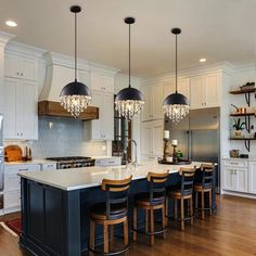 a large kitchen with an island and chandelier hanging from it's ceiling