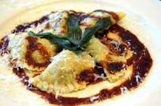 a white plate topped with ravioli covered in sauce