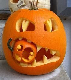 a carved pumpkin with its mouth open and teeth missing, sitting on the steps outside