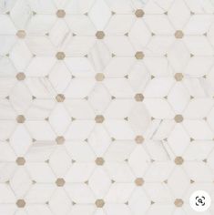 a white and gold tiled wall with hexagonal tiles on it's sides