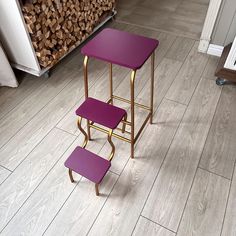 two purple stools sitting next to each other on top of a wooden floor with logs in the background