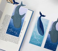 an open book with three whale cards on it