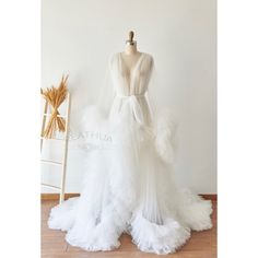 a white wedding dress on a mannequin in front of a wall with a chair