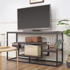 a flat screen tv sitting on top of a metal stand next to a potted plant