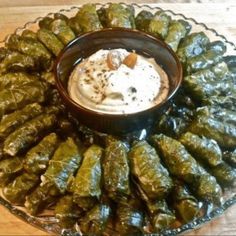 a platter filled with stuffed grape leaves and dip