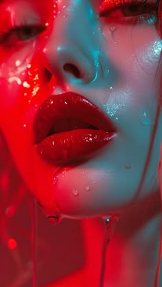 a woman's face is covered in red and blue light while dripping water from her mouth