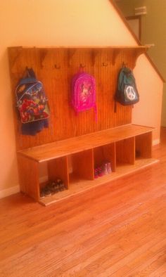 a wooden bench sitting in the middle of a room with two backpacks on it