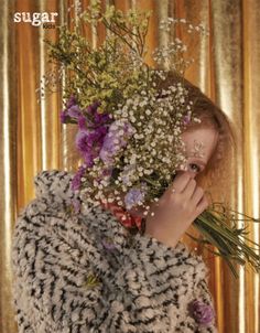 a woman with flowers covering her face in front of a gold background and the words sugar on it