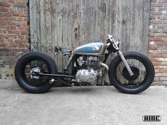 an old motorcycle parked in front of a wooden door with brick walls and doors behind it