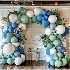 a large balloon arch is decorated with blue, white and green balloons in the shape of an o