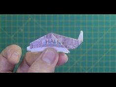 a person is holding a small origami airplane with the word hall written on it