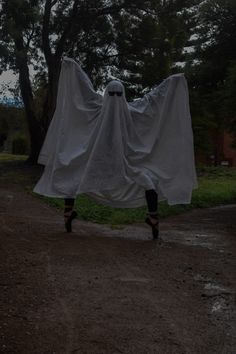 a person dressed as a ghost walking down a dirt road