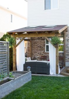 an outdoor living area with a couch and table in the grass next to a house