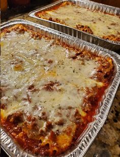 two pans filled with lasagna casserole sitting on top of a counter