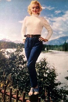 a woman standing on top of a wooden fence