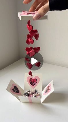 someone is placing hearts on top of a card box to make it look like they are falling