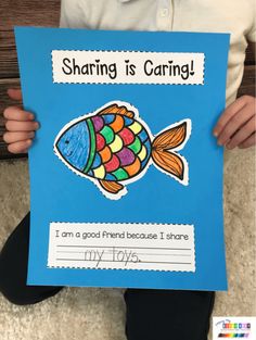 a child holding up a card that reads sharing is caring i am a good friend because it share my toys