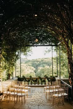 an outdoor venue set up for a wedding ceremony with white chairs and greenery on the walls