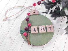 the word joy spelled with scrabbles on a wooden board next to a potted plant