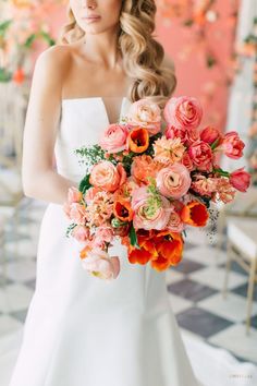 a woman in a white dress holding a bouquet of pink and orange flowers on her wedding day