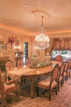 an elegant dining room with chandelier and table surrounded by pink upholstered chairs