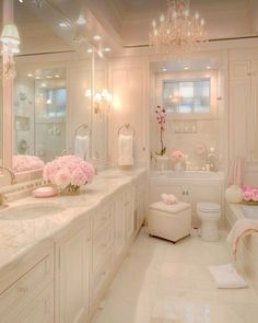 a white bathroom with chandelier and pink flowers