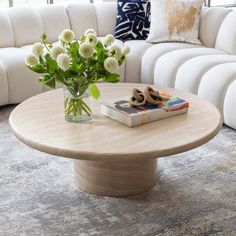 a vase with flowers on top of a coffee table in front of a white couch