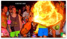 a man holding a large fire ball in front of his face as people look on