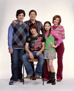 the cast of modern family poses for a portrait in front of a white background, wearing colorful sweaters and jeans