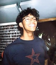 a young man with glasses and a star t - shirt in front of a mirror