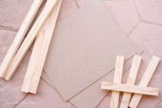 several pieces of wood sitting on top of a stone floor next to a piece of paper