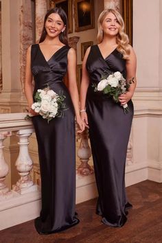 two women standing next to each other wearing black dresses and holding bouquets in their hands