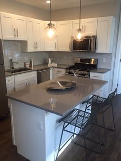 a kitchen with an island and two chairs in front of the counter top, along with white cabinets