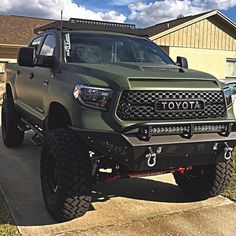 a green toyota truck parked in front of a house