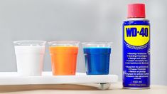 three shot glasses and a bottle of wd 40 on a white table with a gray background