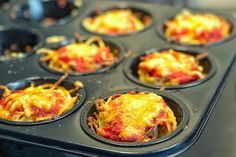 a muffin tin filled with mini pizzas on top of a stovetop oven