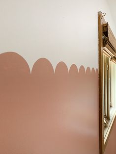 the reflection of a mirror in a pink painted wall with scalloped shapes on it