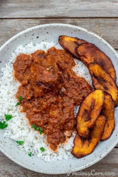 a white plate topped with rice and meat covered in sauce next to sliced banana slices