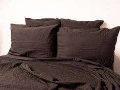 a bed with black sheets and pillows on it