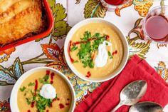 two bowls of soup with sour cream and garnishes on the side next to a red napkin