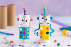 two decorated candles sitting on top of a table next to crayons and markers