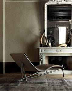 a chair sitting in front of a mirror next to a fireplace