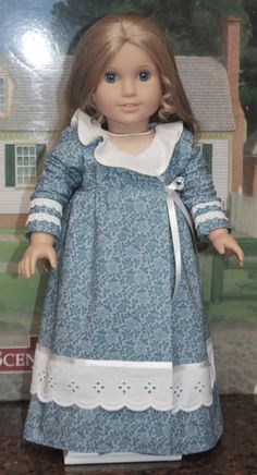 the doll is wearing a blue dress with white trim