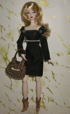 a doll is holding a purse and wearing a black dress