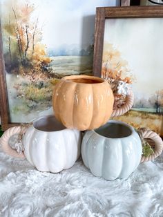 three ceramic pumpkins sitting next to each other on a white furnishing area