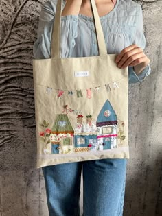 a woman holding a tote bag with houses on it