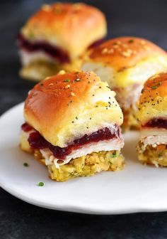 small sandwiches with meat and cheese are on a white plate, ready to be eaten